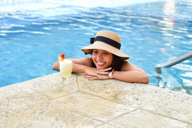 Mujer disfrutando de un cóctel piña colada en la piscina del Hotel La Riviera
