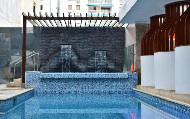 Piscina exterior con cascadas decorativas y mosaico azul del Hotel La Riviera