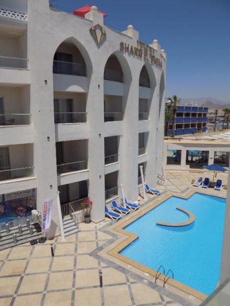 Piscina exterior con tumbonas azules y fachada blanca del Jewel Sharm El Sheikh Hotel en Egipto