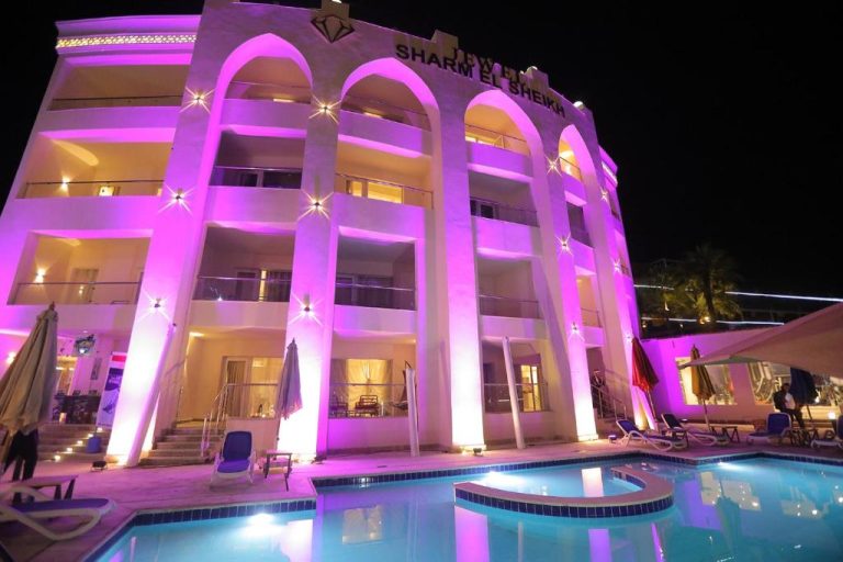 Piscina exterior iluminada de noche con luces rosas del Jewel Sharm El Sheikh Hotel en Egipto