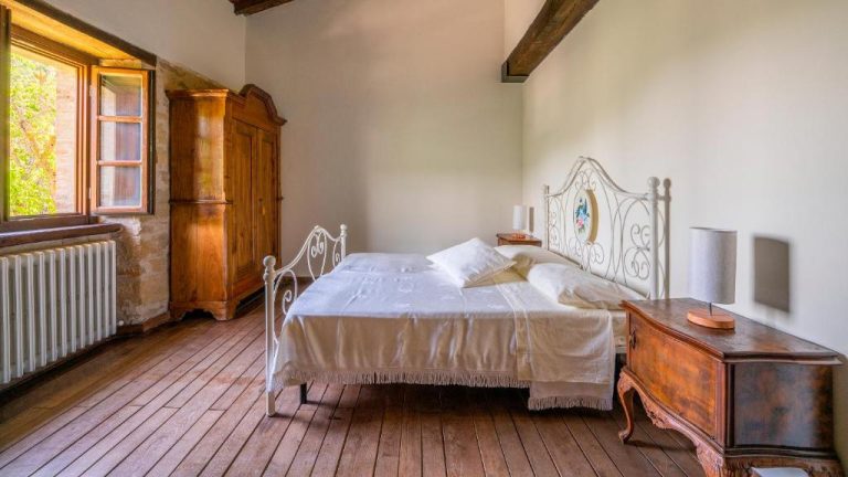 Habitación rústica con cama de hierro forjado y suelo de madera en Agriturismo I Pietrini
