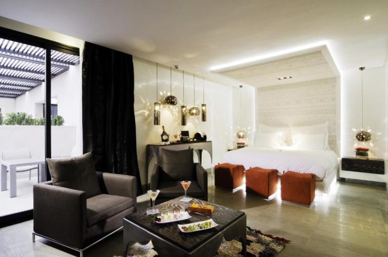 Suite de lujo con zona de estar y cama doble iluminada en Cesar Resort & Spa