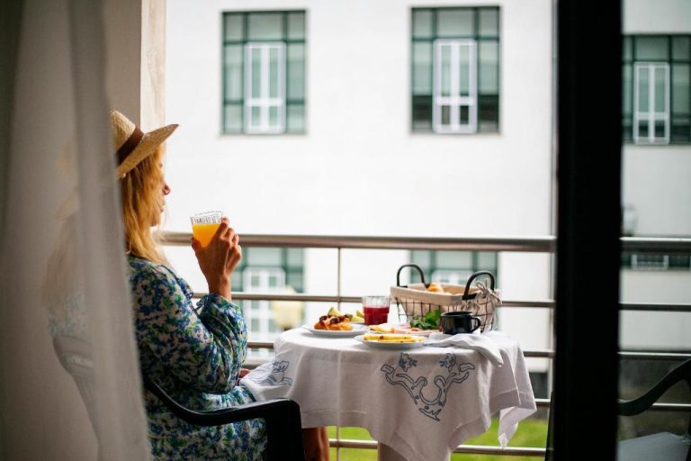 Mujer desayunando en la terraza del Hotel do Mar con zumo de naranja y vistas al edificio