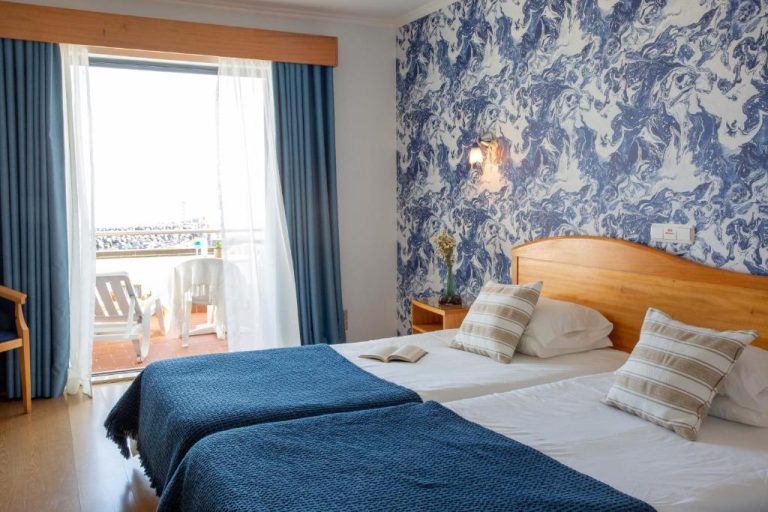 Habitación doble con camas individuales, terraza con vistas al mar y decoración azul en Hotel do Mar