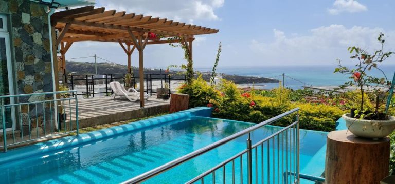 Piscina infinita con terraza y pérgola de madera en Villa Paradise Rodrigues con vistas al océano