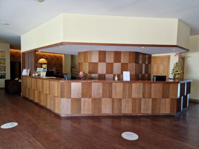 Recepción de madera con diseño en damero del Hotel Da Montanha con personal atendiendo