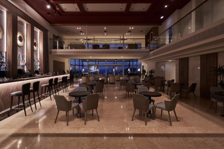 Bar y salón elegante con mesas y terraza nocturna en Atlantica Kalliston Resort Adults Only