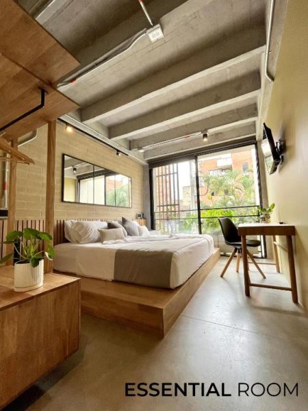 Habitación Essential Room con cama plataforma de madera y escritorio en hotel Beminimal Parques