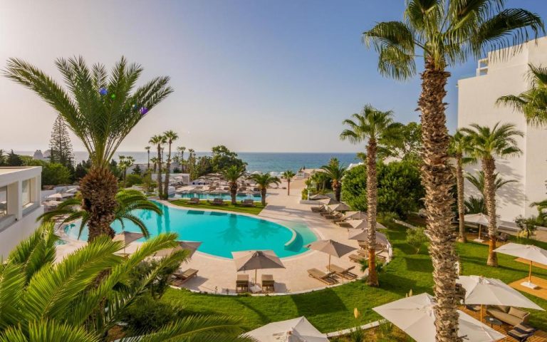 Piscina exterior con tumbonas y palmeras del Royal Azur Thalassa con vistas al mar Mediterráneo