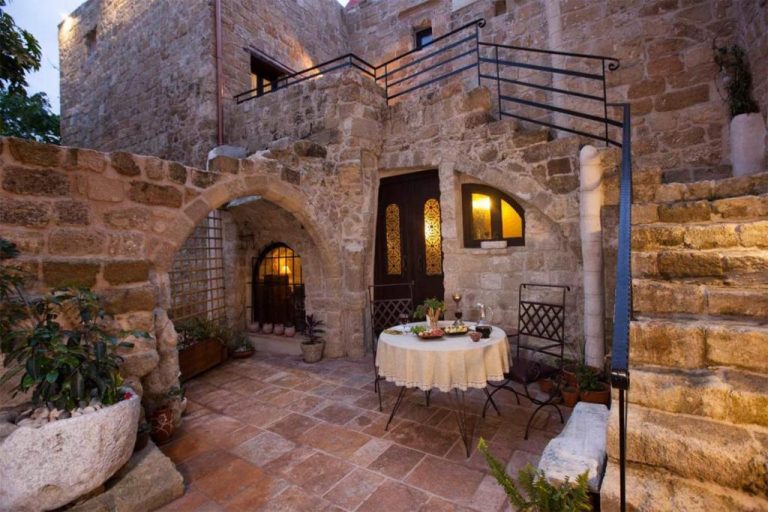 Patio exterior con muros de piedra histórica y mesa romántica del Porolithos Boutique Hotel