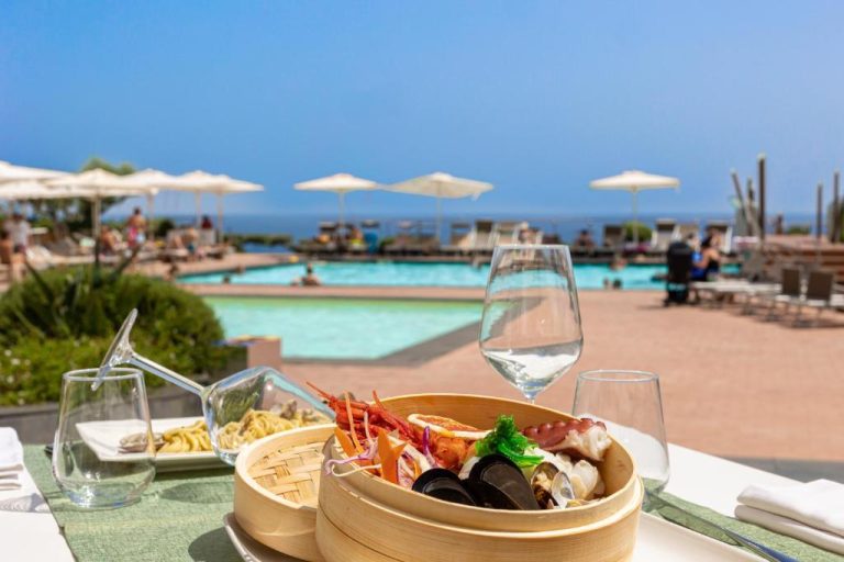Plato de mariscos al vapor con vista a la piscina exterior e mar en Domina Zagarella Sicily
