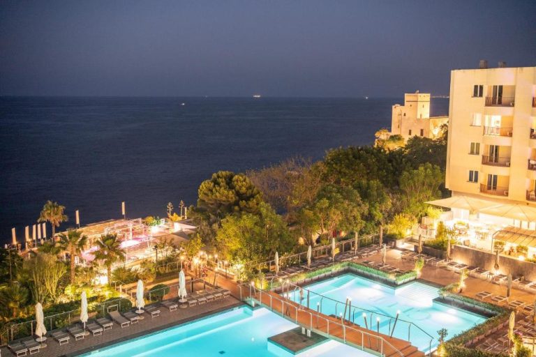 Vista nocturna de la piscina exterior del Domina Zagarella Sicily con vistas al mar Mediterráneo
