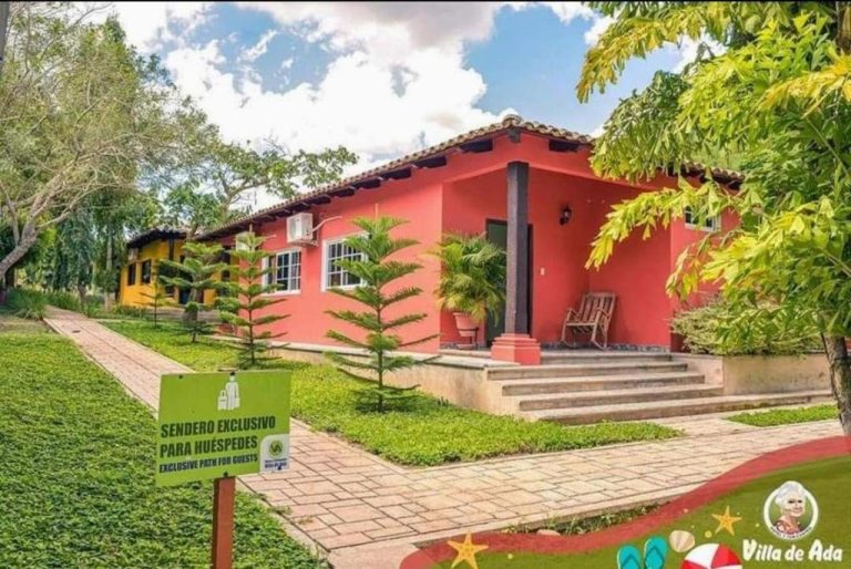 Fachada exterior colorida del Hotel de Campo Villa de Ada con jardines tropicales y sendero exclusivo para huéspedes