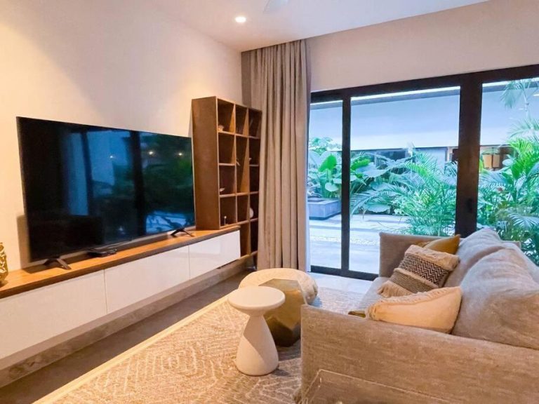 Salón moderno con televisor y sofá del Ipana by Andiani Travel con vista a jardín tropical