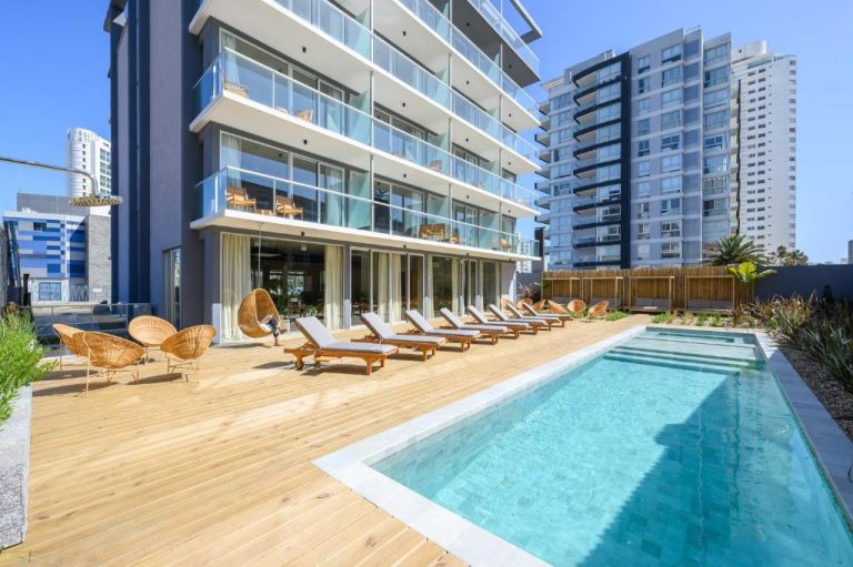 Piscina exterior con tumbonas y terraza de madera del Ambar Hotel rodeada de edificios modernos