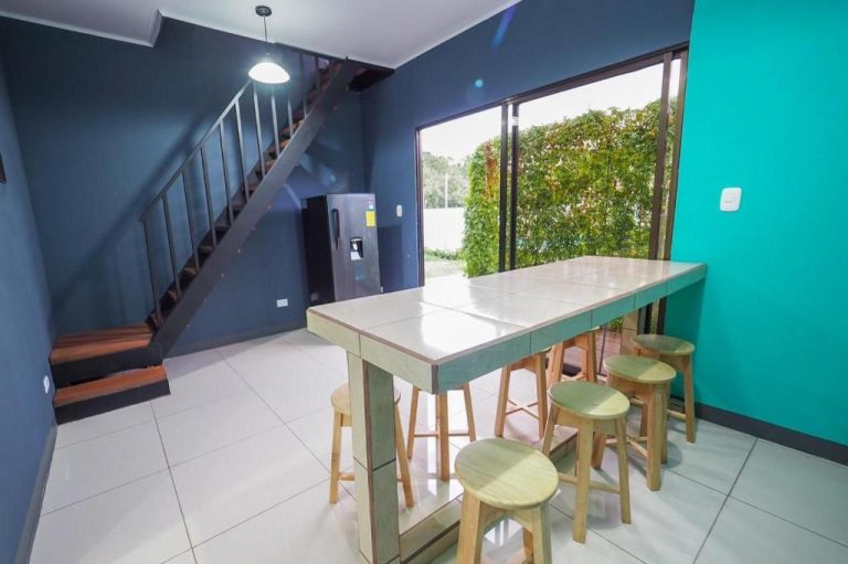 Área de cocina y comedor con barra alta y taburetes en Hotel Sirius Costa Rica con acceso al jardín