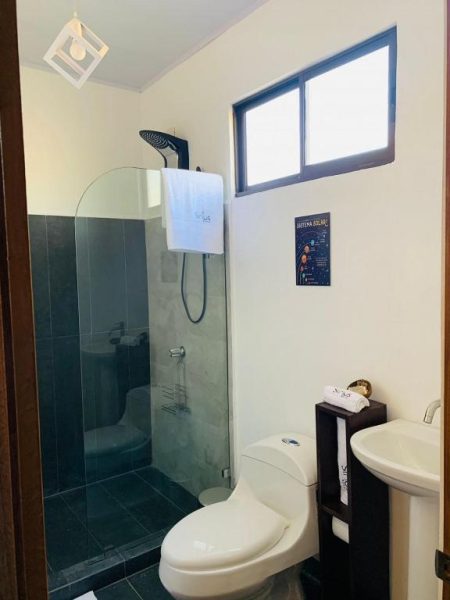 Baño moderno con ducha de cristal y sanitarios blancos en Hotel Sirius Costa Rica