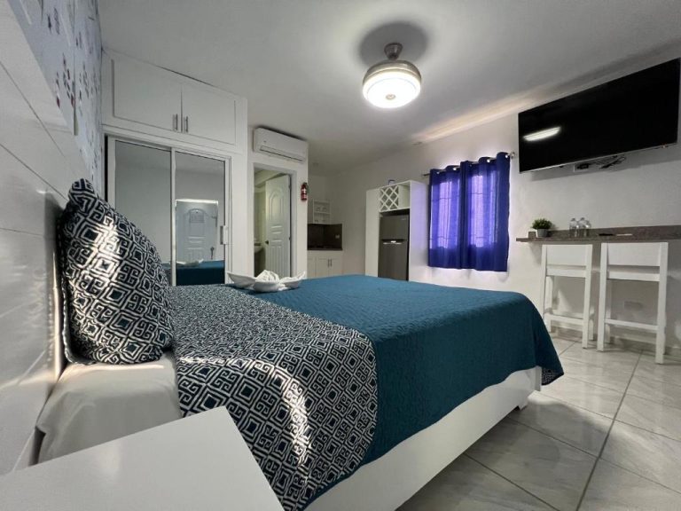 Habitación doble con cama matrimonial, televisor y cocina en Costa Love Hotel Aeropuerto