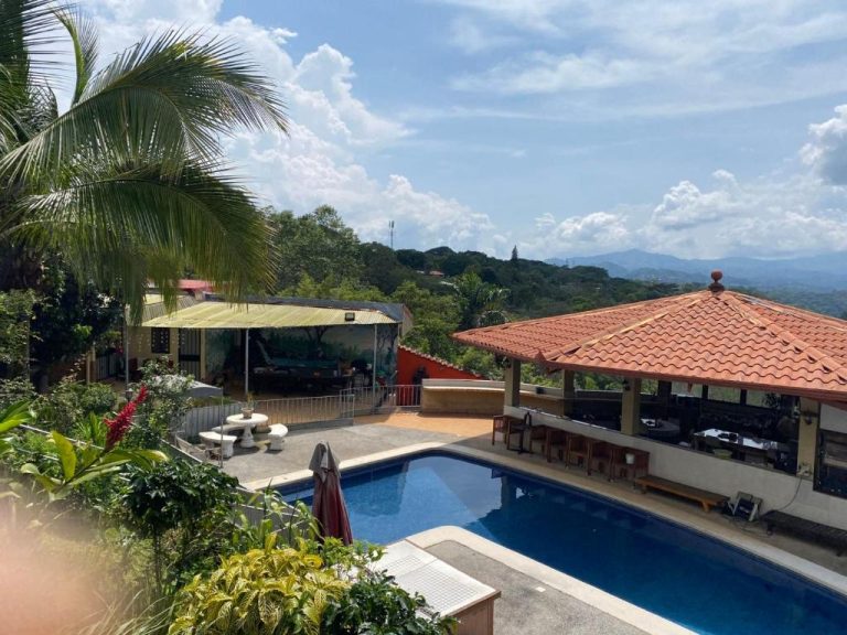 Piscina exterior con bar y terraza del Villa Garita Inn rodeada de vegetación tropical y vistas a las montañas