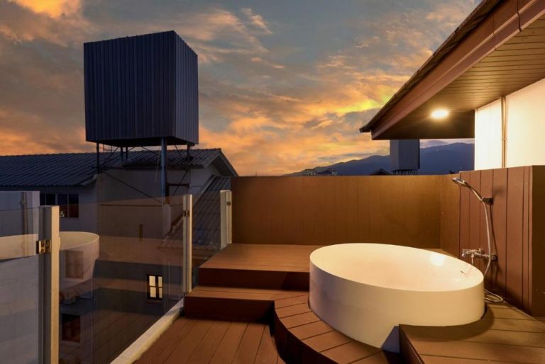 Bañera exterior en terraza de madera con vistas al atardecer en Be Phrasingh Hotel Chiang Mai