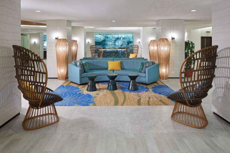 Elegante lobby lounge del OUTRIGGER Waikiki Beachcomber Hotel con sofá azul y sillas de ratán