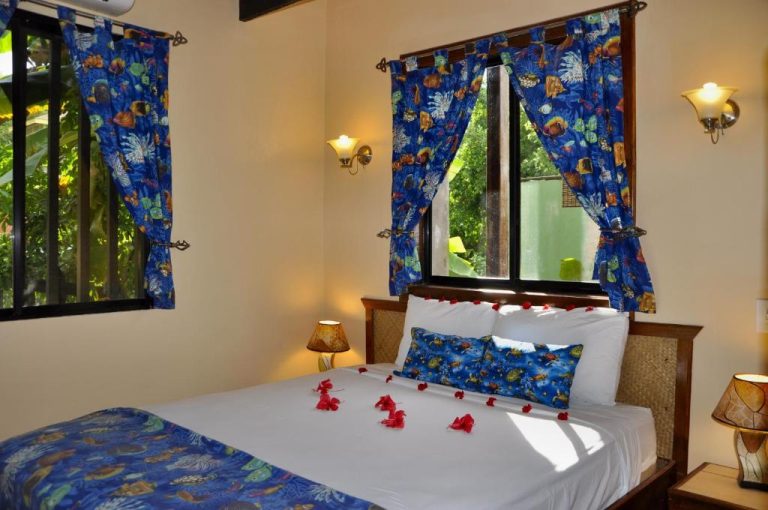 Habitación decorada con flores rojas y cortinas tropicales en West Bay Lodge and Spa