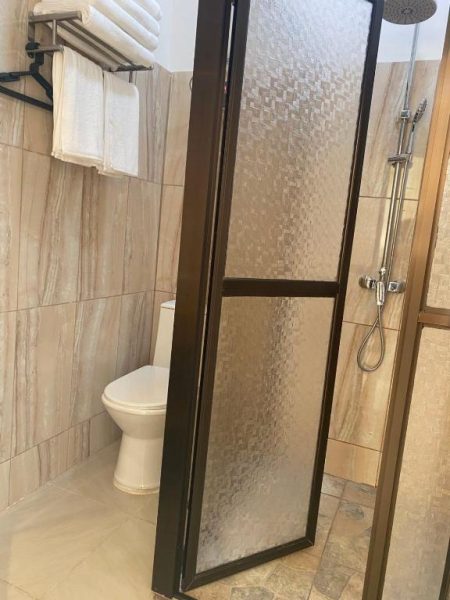 Baño privado con ducha independiente de cristal y toallas en Villa Garita Inn