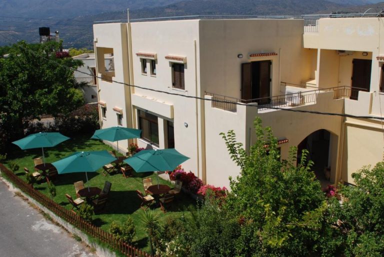 Jardín exterior con sombrillas y tumbonas del Aptera Hotel con vistas a las montañas de Creta