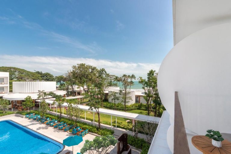 Piscina exterior con tumbonas azules y vistas al mar del Avani Chaweng Samui Hotel & Beach Club