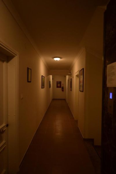 Pasillo interior iluminado del Narcis Apart Hotel con suelo oscuro y cuadros decorativos en las paredes