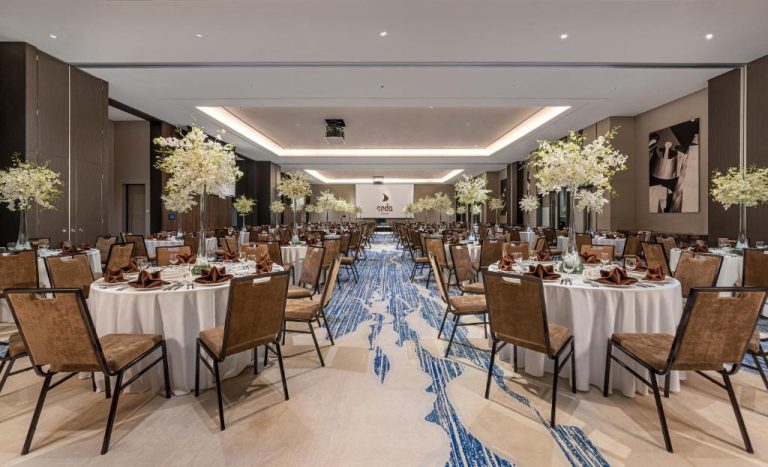 Salón de banquetes elegante con mesas redondas y flores blancas en el Hotel Seda Nuvali Laguna