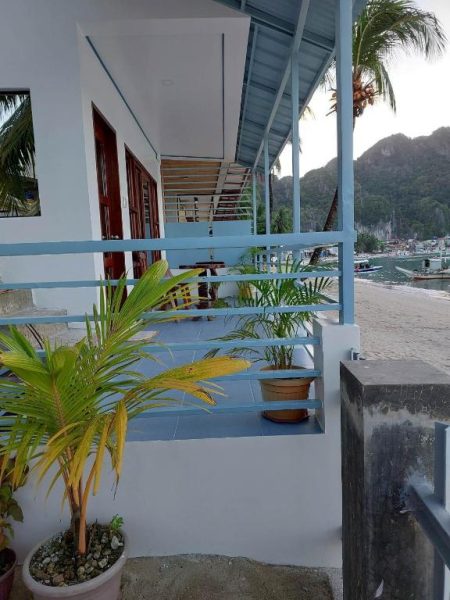 Terraza con vistas a la playa y montañas del Chislyk Inn con palmeras y zona de descanso