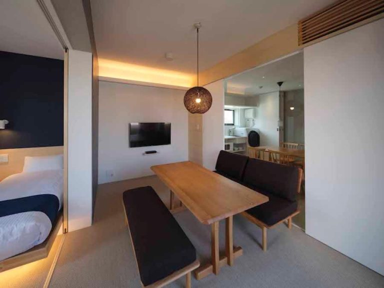 Suite con salón comedor, mesa de madera y zona de dormitorio separada en East Square Tokyo