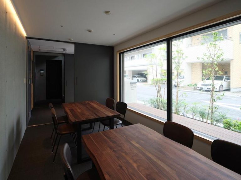 Sala comedor con mesas de madera y amplio ventanal con vistas a la calle en East Square Tokyo