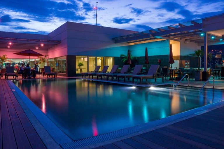 Piscina en la azotea del Hyatt Place Tegucigalpa iluminada de noche con área de descanso y bar
