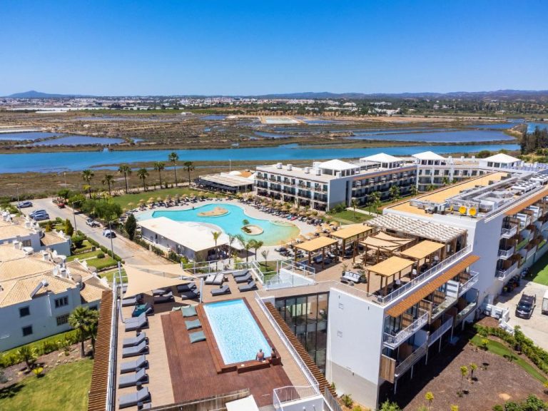 Vista aérea de las piscinas exteriores y zona de descanso del AP Cabanas Beach & Nature con laguna al fondo