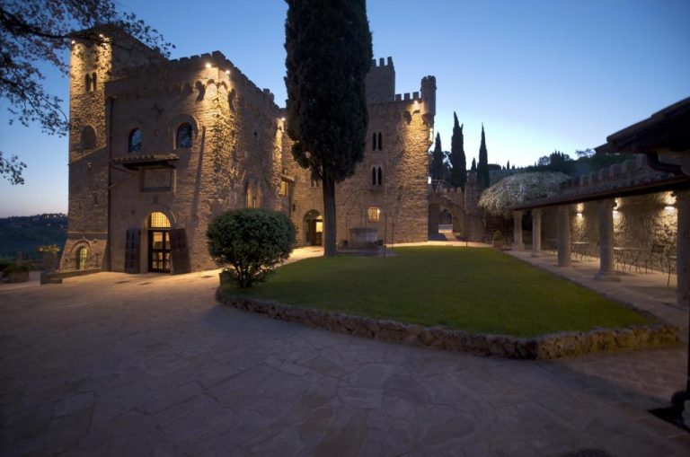 Fachada exterior iluminada del castillo medieval TH Perugia Castello di Monterone al atardecer