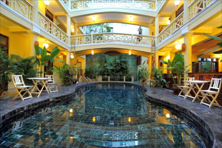 Piscina interior con atrio tropical y balcones coloniales en el Thanh Van 1 Hotel de Vietnam