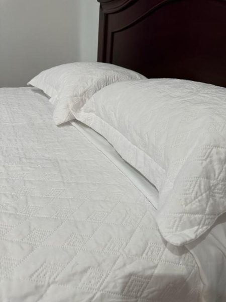 Cama doble con ropa de cama blanca y cabecero de madera oscura en Hotel Real Paraíso