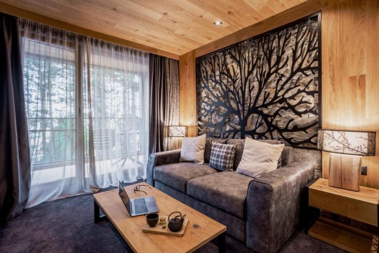 Salón con sofá y decoración de madera rústica con arte mural de árbol en Kashmir Wellness SPA Hotel