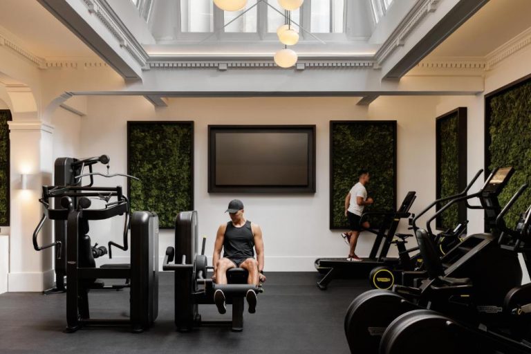 Gimnasio moderno del Capella Sydney con máquinas de musculación, cintas de correr y paredes verdes decorativas