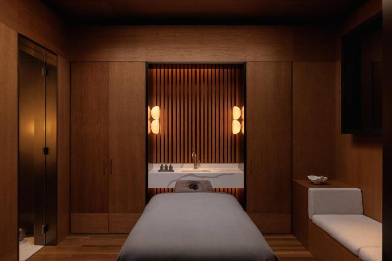 Sala de tratamientos y masajes del Spa en Capella Sydney con camilla y paredes de madera