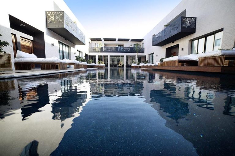 Piscina interior con tumbonas y terrazas del Cesar Resort & Spa rodeada de arquitectura moderna