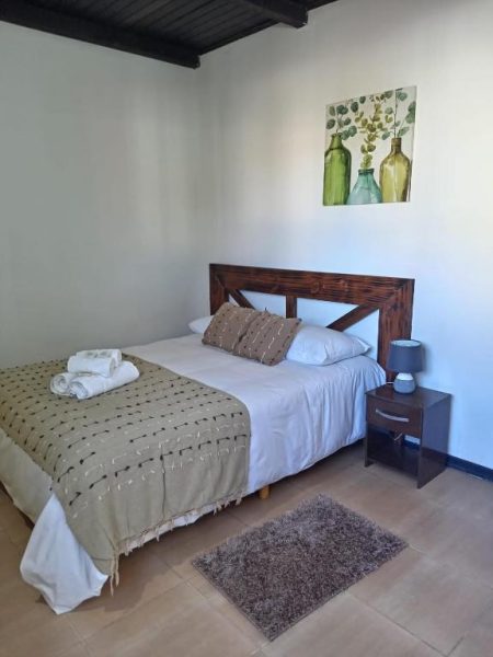 Habitación con cama matrimonial y cabecera de madera en Posada Don Manuel, decoración rústica acogedora