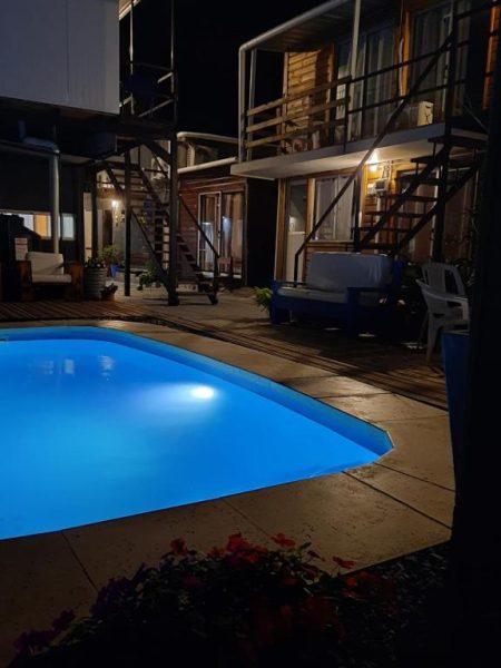 Piscina iluminada de noche en la Posada Don Manuel con vista a las cabañas y balcones del alojamiento