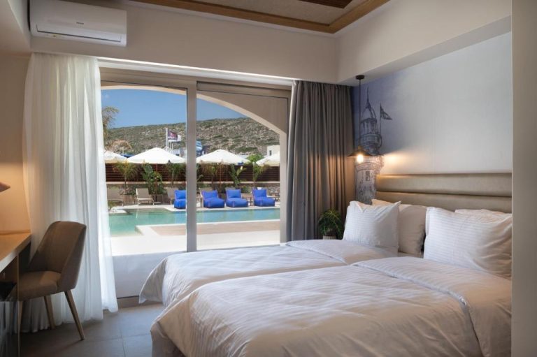 Habitación doble con camas blancas y vistas a la piscina exterior en Prasonisi Lighthouse Boutique Hotel