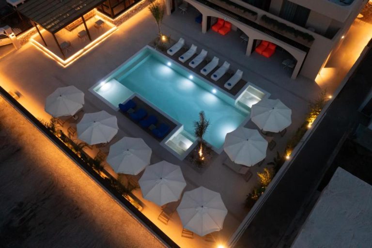 Piscina iluminada de noche con sombrillas blancas y tumbonas en Prasonisi Lighthouse Boutique Hotel