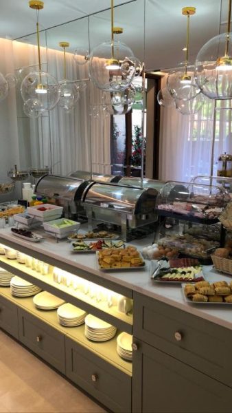 Buffet de desayuno con variedad de alimentos y lámparas de cristal en Hotel Villa Gracia