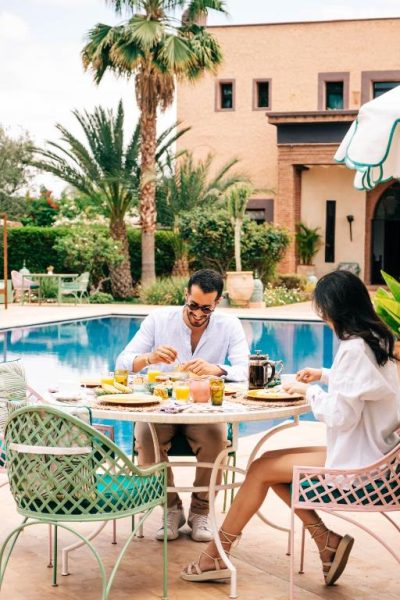 Pareja desayunando junto a la piscina exterior de La Villa Des Golfs & PinkCactus en Marrakech