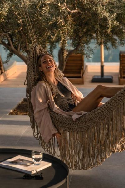 Mujer relajada en hamaca de macramé junto a la piscina del Cook's Club Kolymbia Rhodes